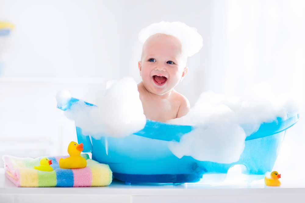 Glad skrattande baby tar ett bad leker med skum bubblor